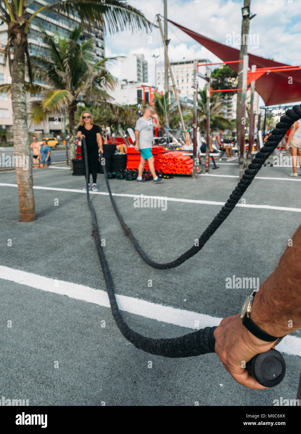 Modello rilasciato: Uomo azienda combattendo la corda con la donna più anziana (70-79) sullo sfondo a palestra pubblica a Ipanema, Rio de Janeiro, Brasile Foto Stock