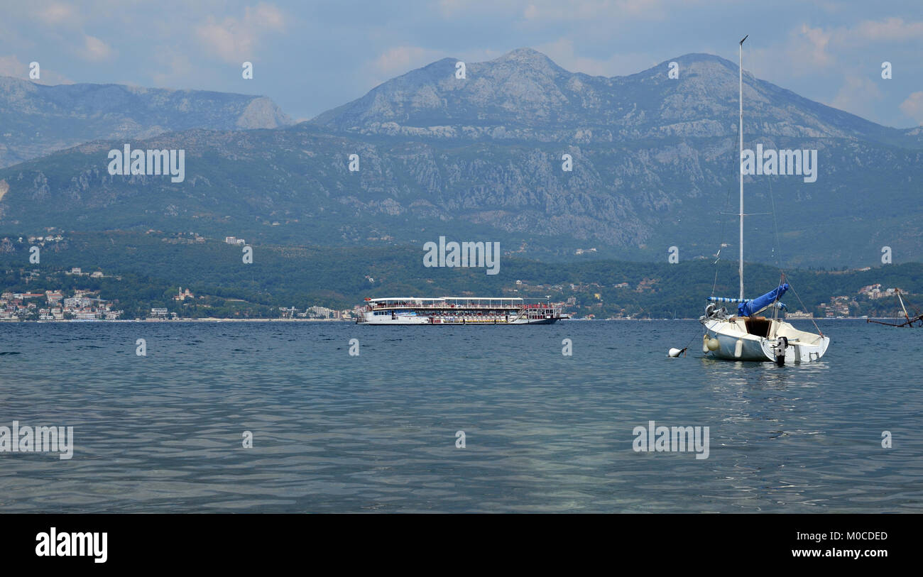 Imbarcazione turistica mentre la vela su un mare calmo superficie con piccoli villaggi costieri in una distanza Foto Stock