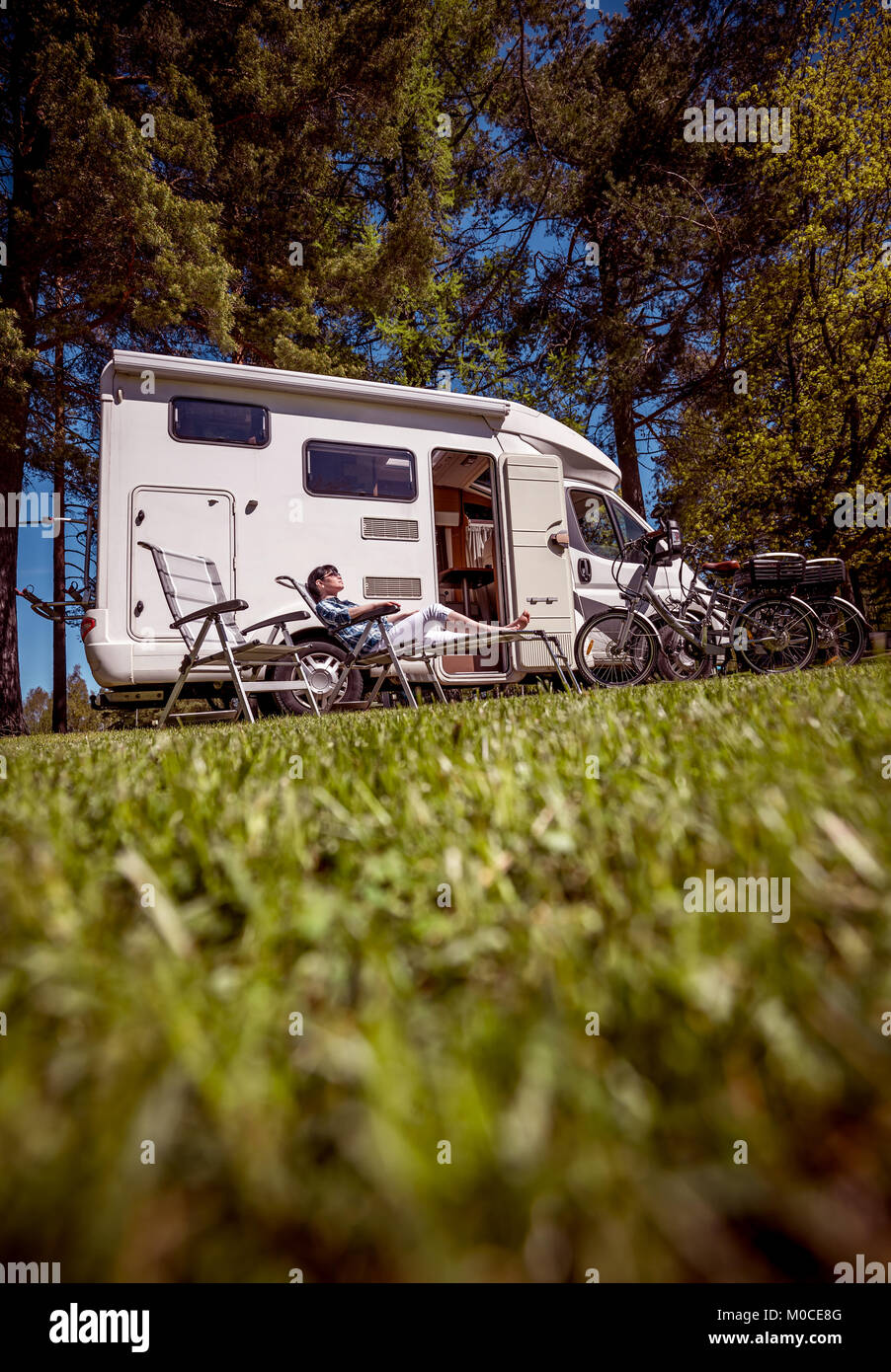 Donna adagiata vicino i camper in natura. Vacanza per la famiglia in viaggio, viaggio vacanza in camper RV, Caravan auto vacanza. Foto Stock