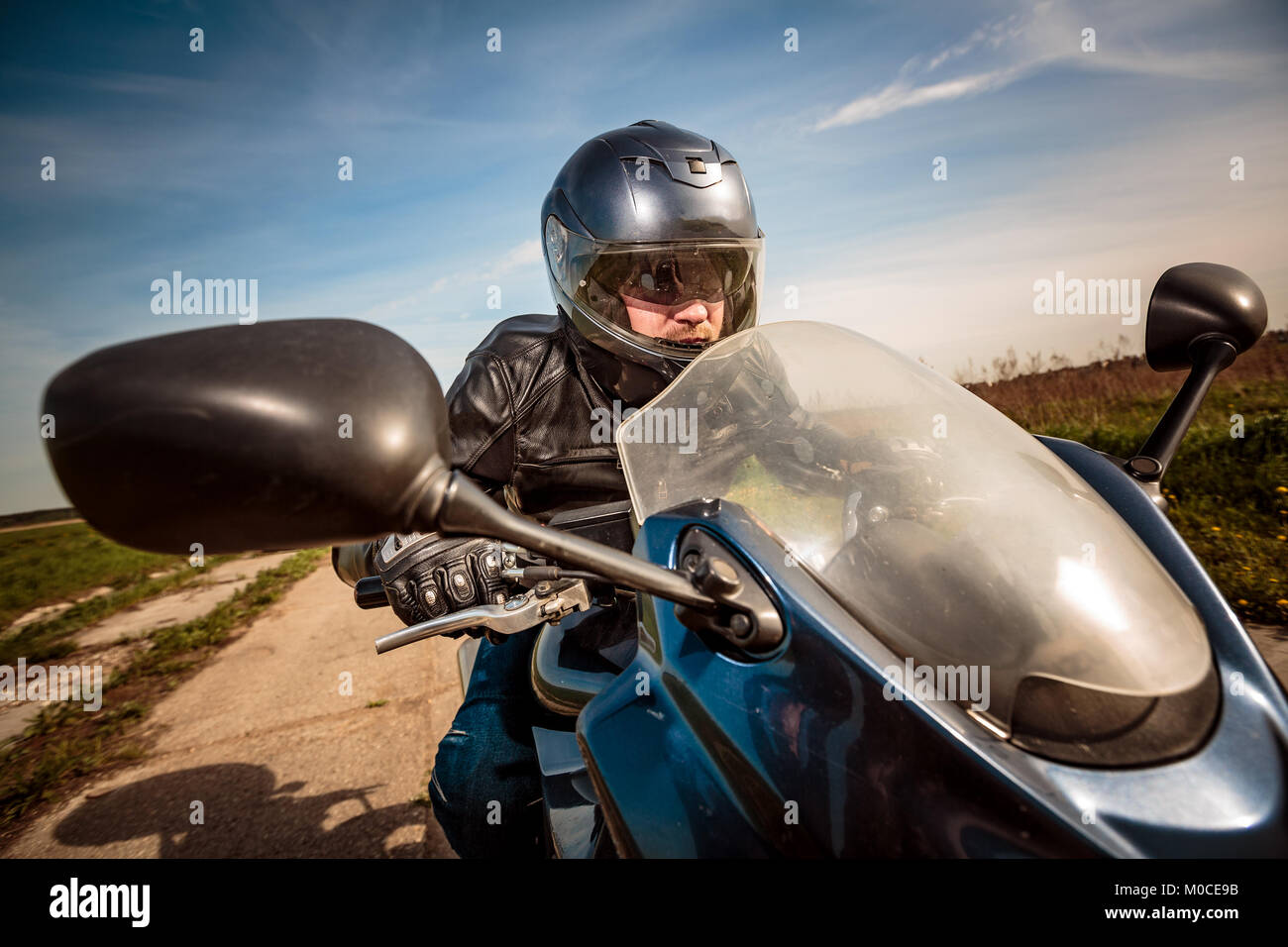 Biker in casco e giacca di pelle racing su strada Foto Stock Biker in casco e giacca di pelle racing su strada Foto Stock