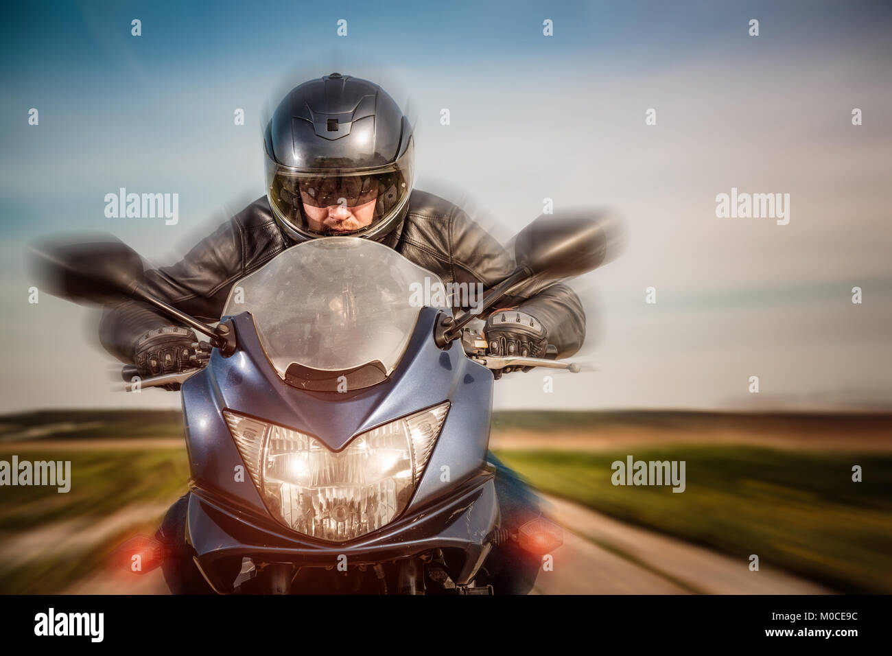 Biker in casco e giacca di pelle racing su strada Foto Stock Biker in casco e giacca di pelle racing su strada Foto Stock