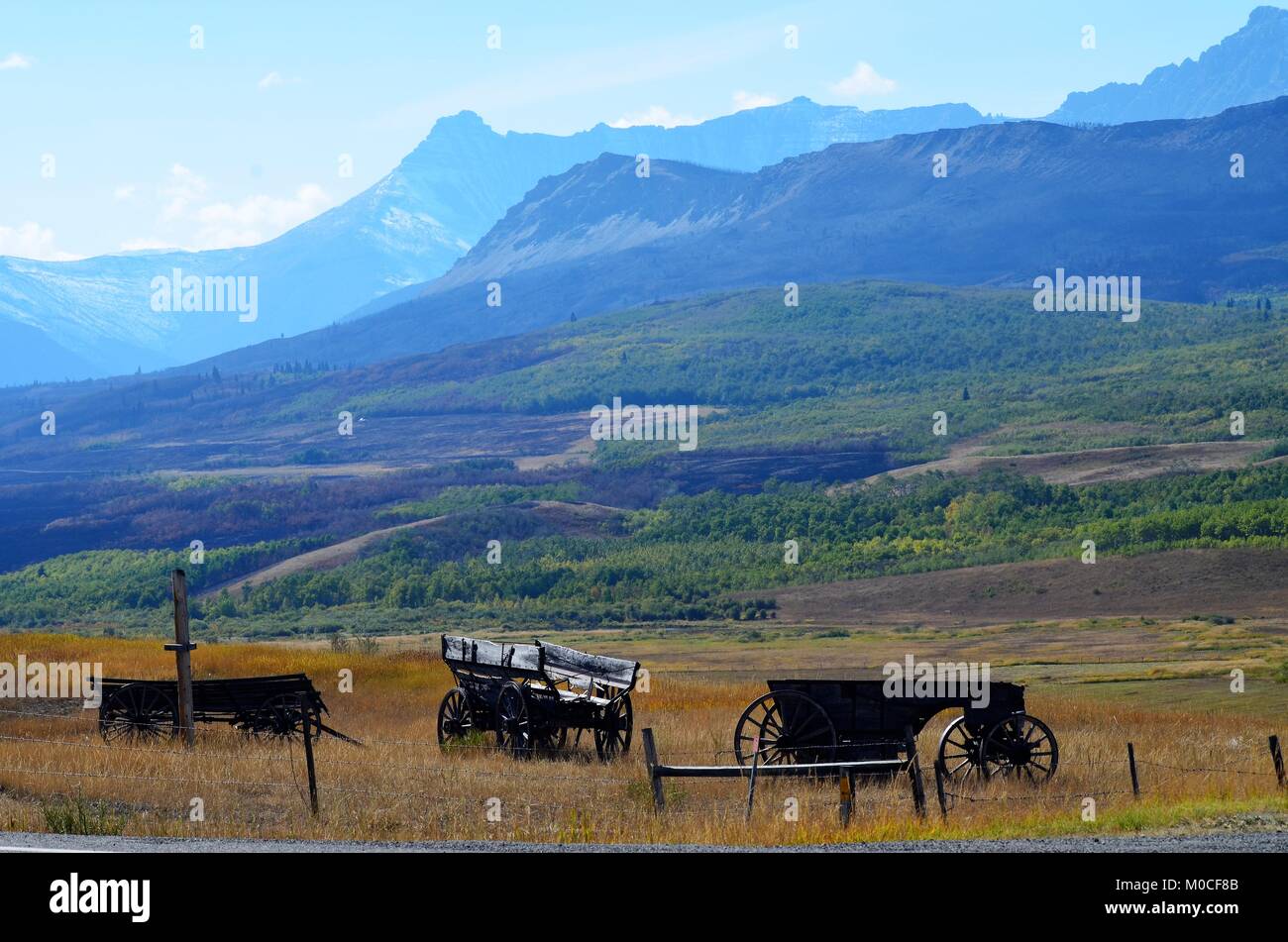 Sulla cima di una collina e si trova a tre antichi carri di legno, dal cowboy giorni, con un incredibile di montagna e di valle vista del paesaggio Foto Stock
