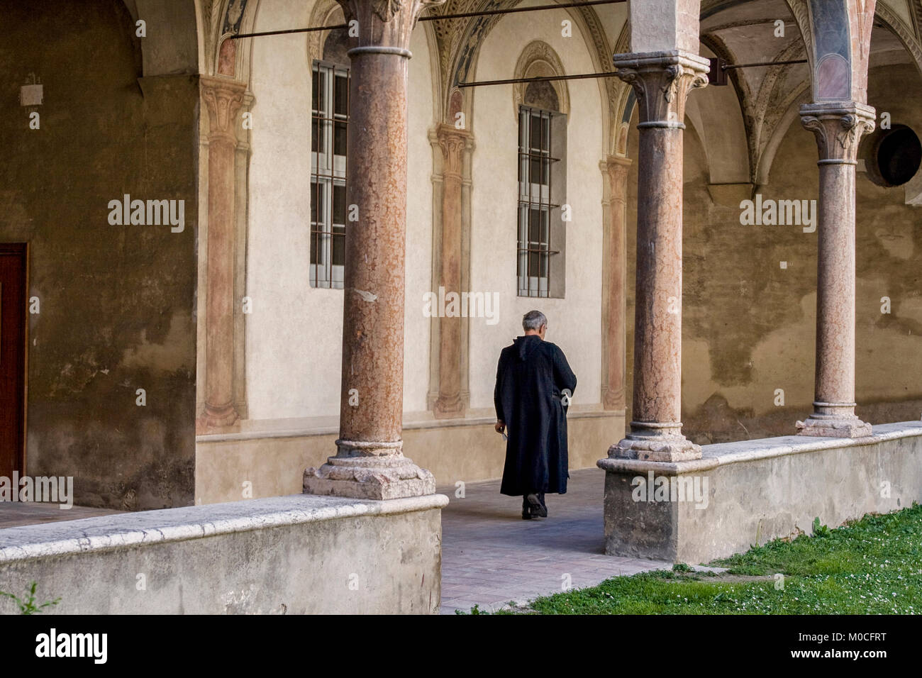 Italiano convento medievale a Parma con il sacerdote a piedi nella loggia Foto Stock