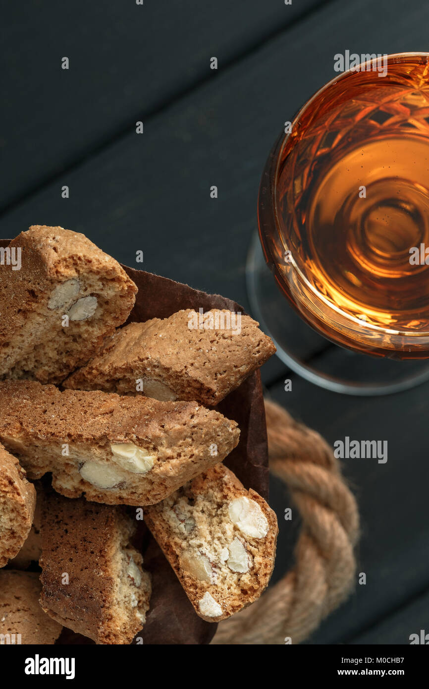 Italian cantuccini biscotti e un bicchiere di vin santo vino su sfondo di legno Foto Stock