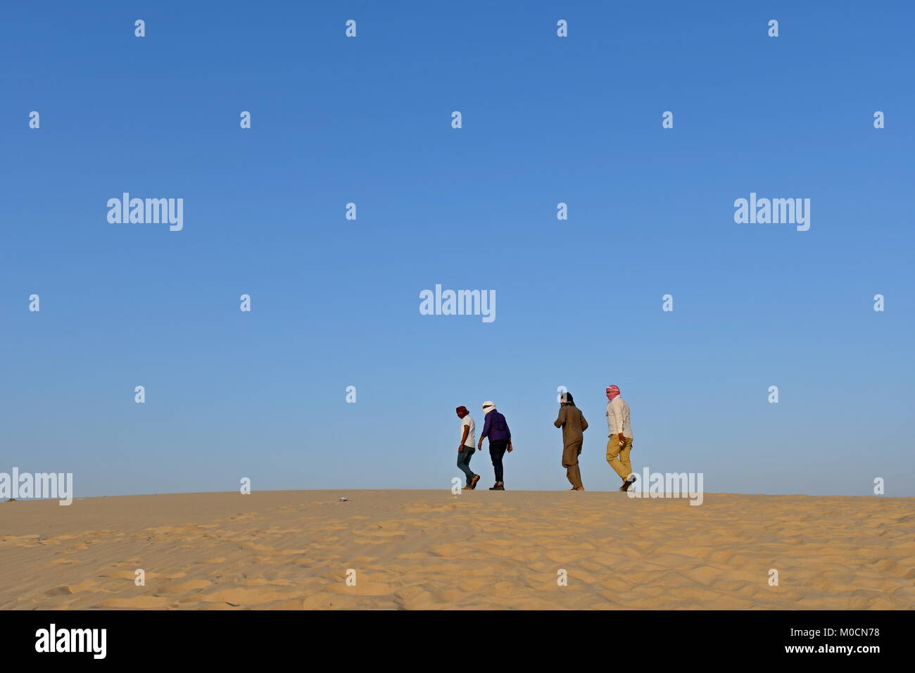 Gli uomini nel deserto di sabbia giocando ed appendere fuori con i telefoni cellulari e rendendo selfies Foto Stock