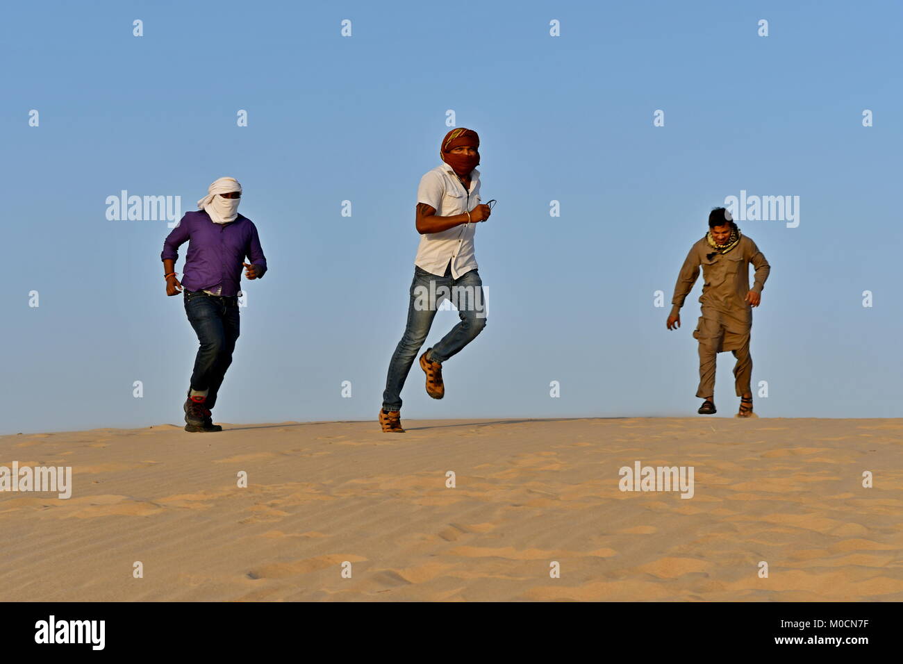 Gli uomini nel deserto di sabbia giocando ed appendere fuori con i telefoni cellulari e rendendo selfies Foto Stock