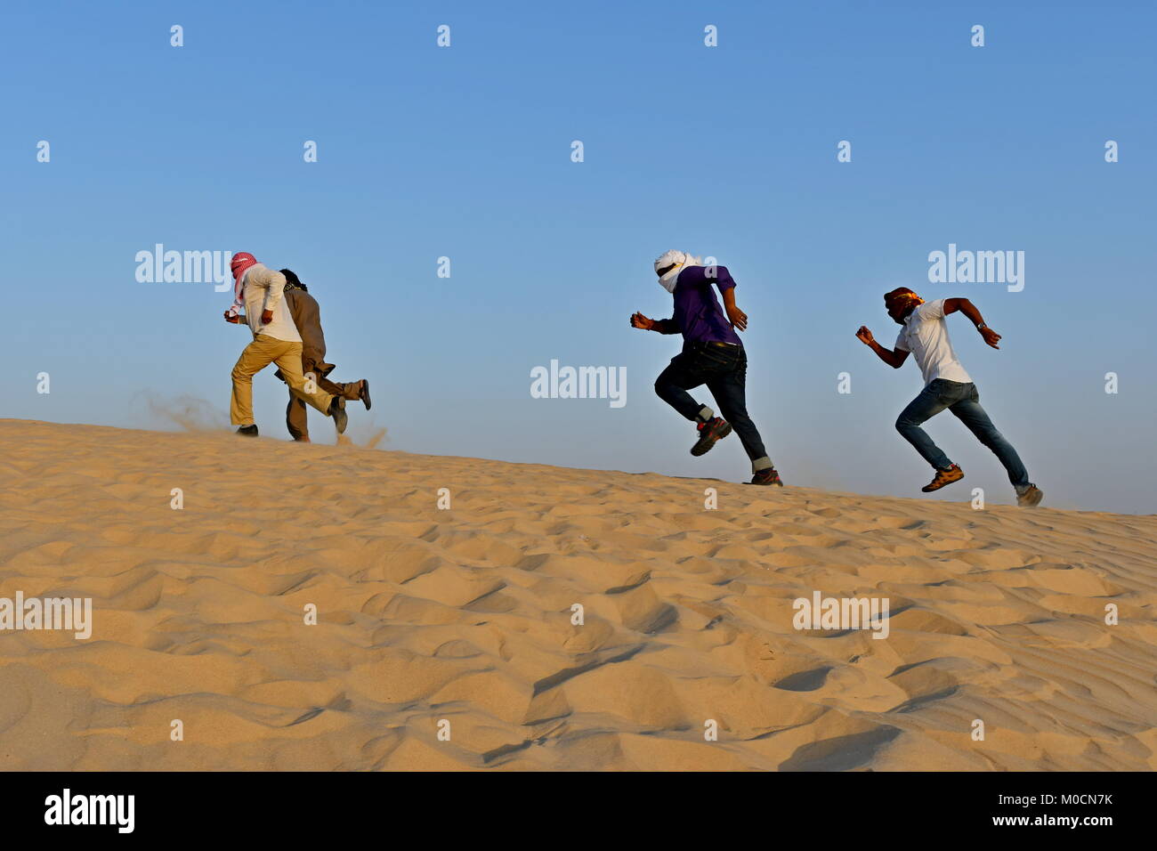 Gli uomini nel deserto di sabbia giocando ed appendere fuori con i telefoni cellulari e rendendo selfies Foto Stock