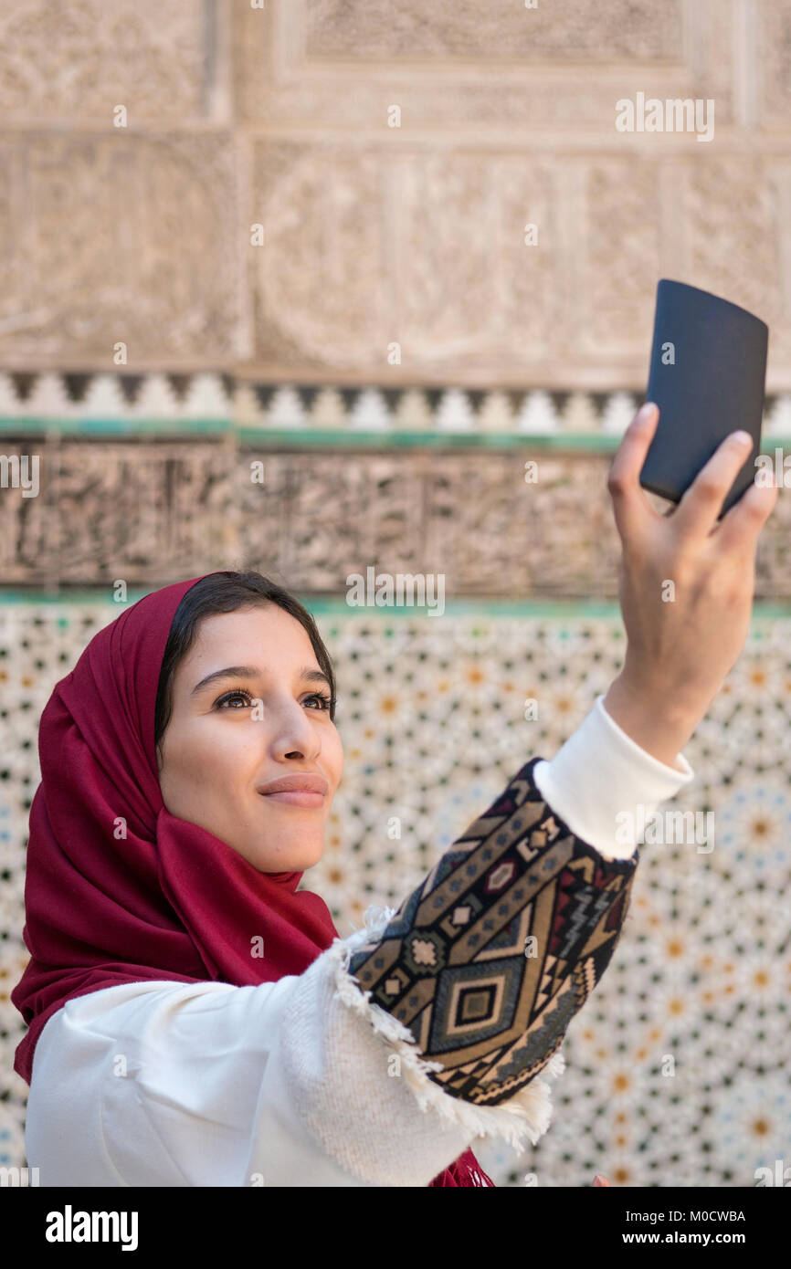 La donna araba in abbigliamento tradizionale tenendo selfie con telefono mobile Foto Stock