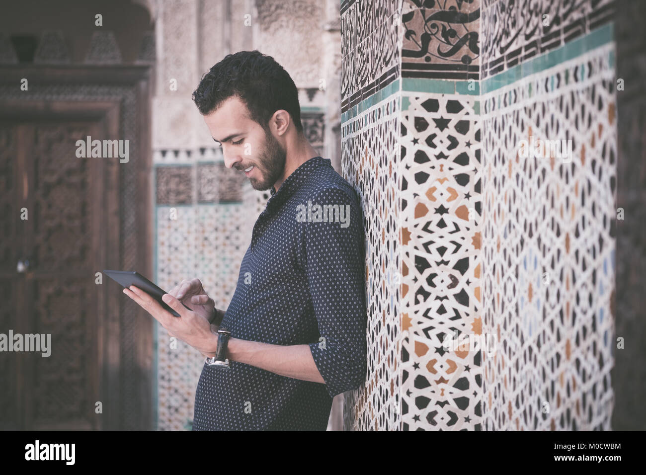 Giovane uomo arabo lavorando su tablet Foto Stock