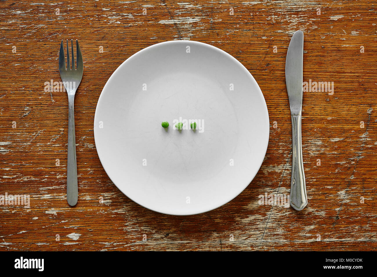 Tre piselli verdi su un piatto, forchetta e coltello sul tavolo, dieta e  perdere il concetto di peso, stile di vita sano Foto stock - Alamy