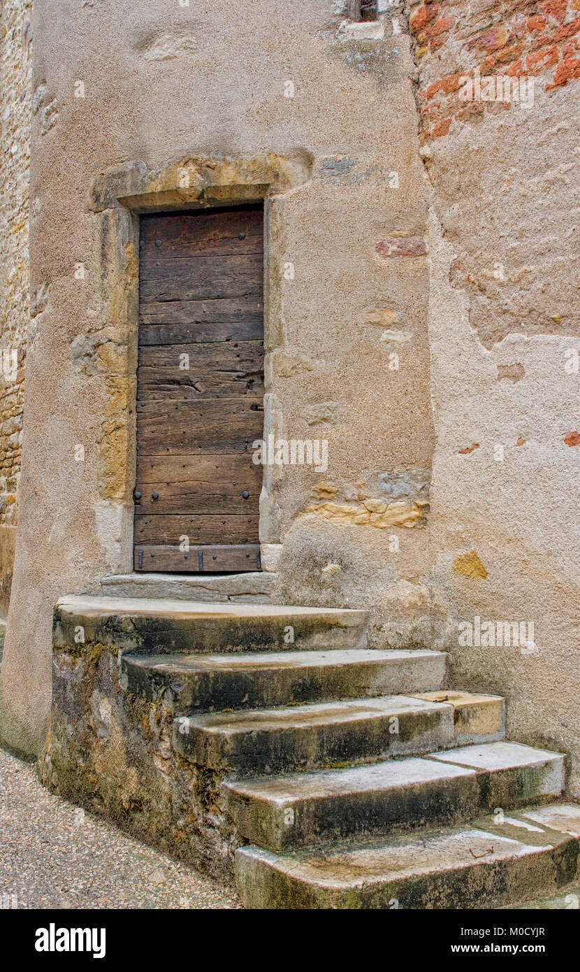 Cinque alterate di gradini di pietra di un vecchio legno porta anteriore in una cittadina francese Foto Stock