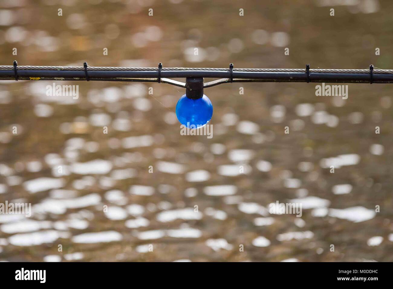 Singola lampada elettrica appesa sopra un ruscello o fiume. Foto Stock