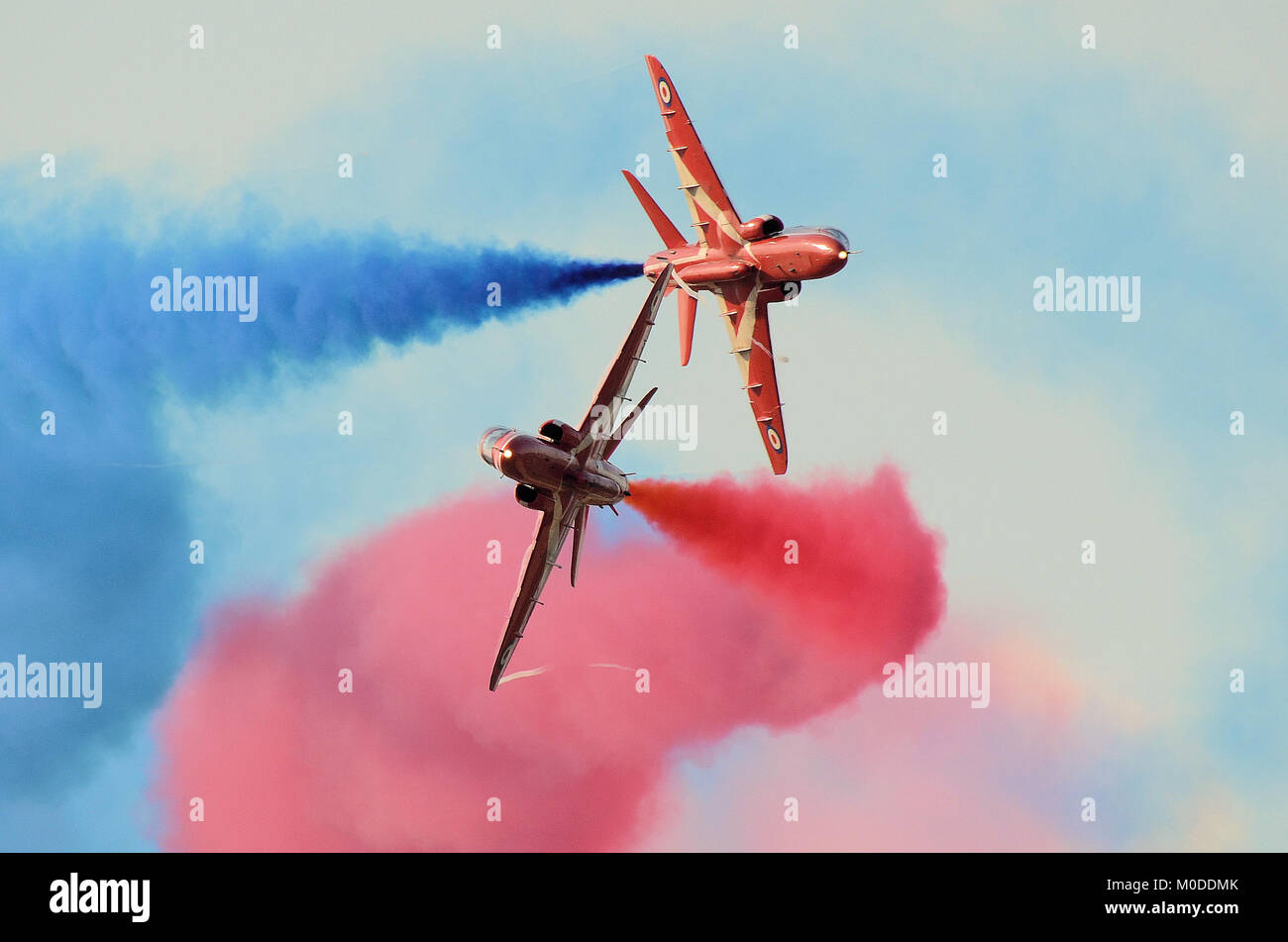 Le frecce rosse synchro coppia eseguendo una ripartizione dinamica manovra a un'esibizione aerea con il rosso e il blu di fumo e di wingtip vortici. Royal Air Force team display Foto Stock