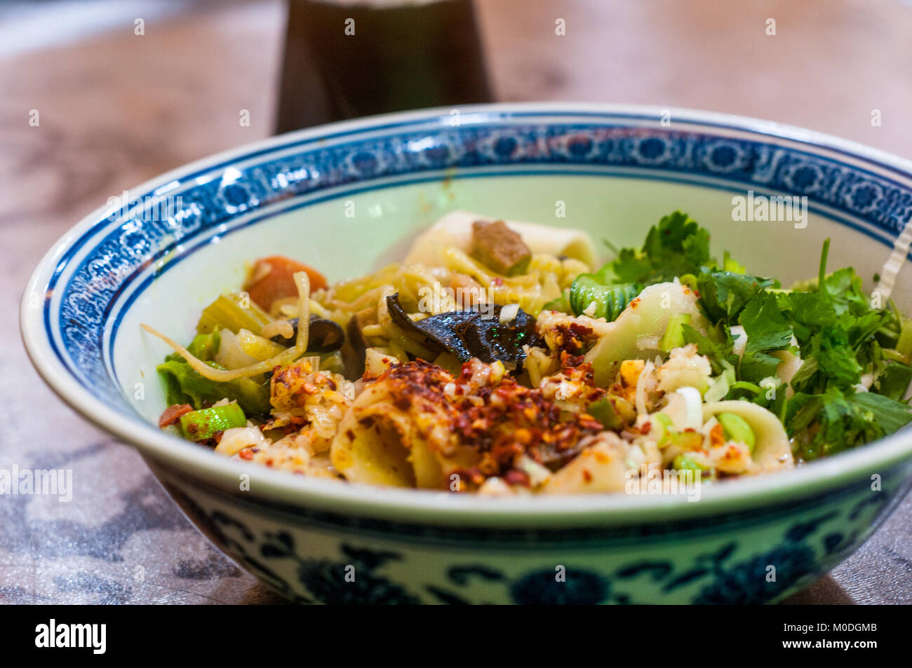 Una ciotola di biang biang noodles nel Quartiere Musulmano di Xi'an, Cina. Sour succo di prugna bere dietro. Foto Stock