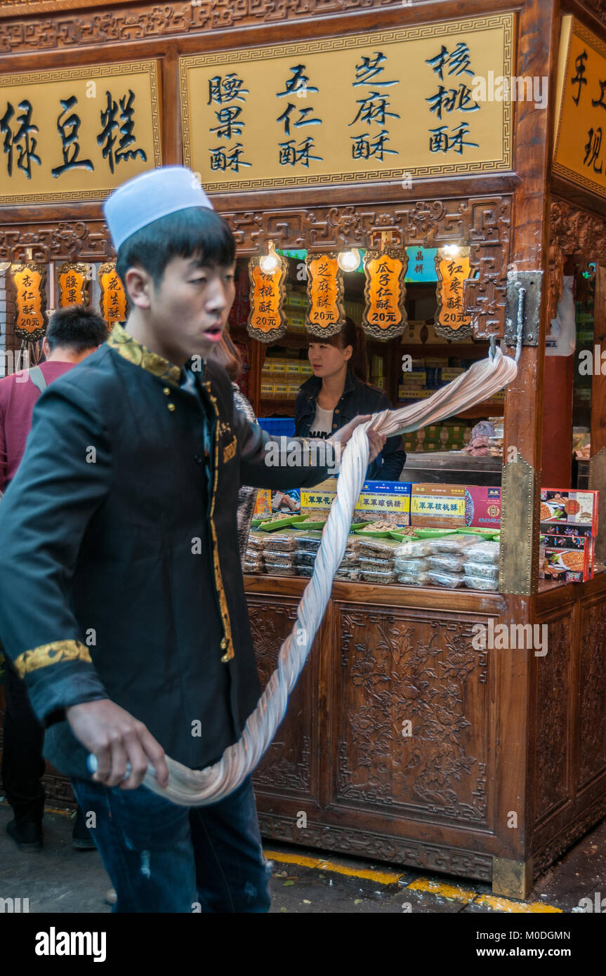 Rendendo martellato candy sulla strada. Beiyuanmen Street nel Quartiere Musulmano, Xi'an, Shaanxi Province, Cina. Foto Stock