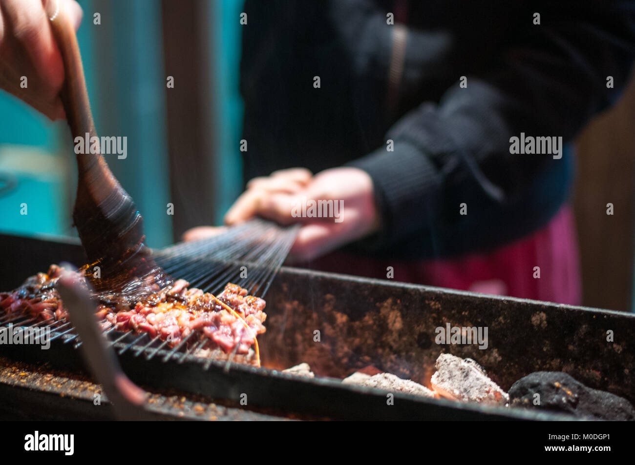 Un uomo alla brace piccoli spiedini di carne su spiedini di metallo tra i vicoli del quartiere musulmano di Xi'an, Cina. Uno di una serie di tre. Come ha visitato o Foto Stock