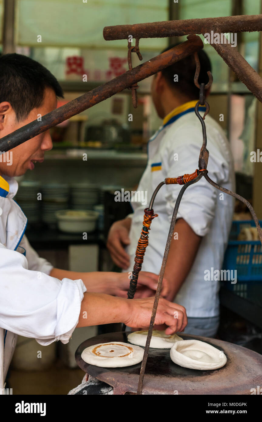 La cottura del pane mo per roujiamo nel modo tradizionale in salsa Wangkui Salumi Roujiamo ristorante a Xi'an, Shaanxi Province, Cina. Foto Stock