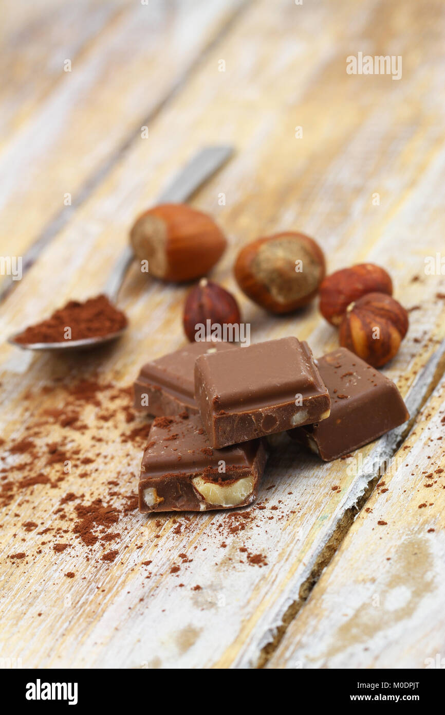 Pezzi di cioccolato croccante con nocciole intere su rustiche superficie in legno Foto Stock