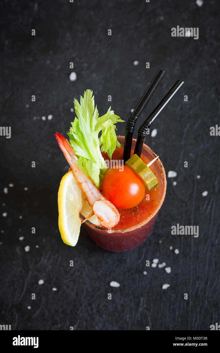 Bloody Mary cocktail in vetro con contorni. Il pomodoro Bloody Mary bevanda piccante su sfondo nero con copia spazio. Foto Stock