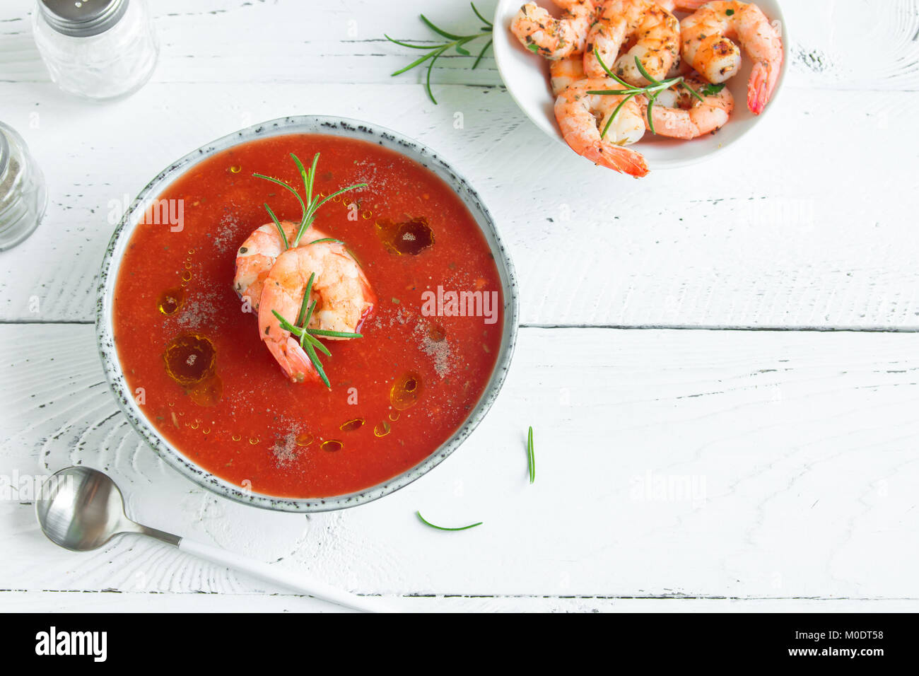 Vegetali zuppa di pomodoro gazpacho con gamberi, olio di oliva e rosmarino in ciotola di legno bianco sfondo, vista dall'alto, copia dello spazio. Foto Stock