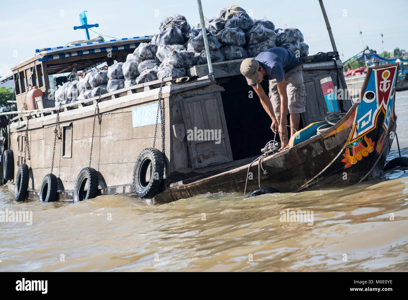 L'uomo le funi di legatura su una chiatta sul fiume, Vietnam Foto Stock