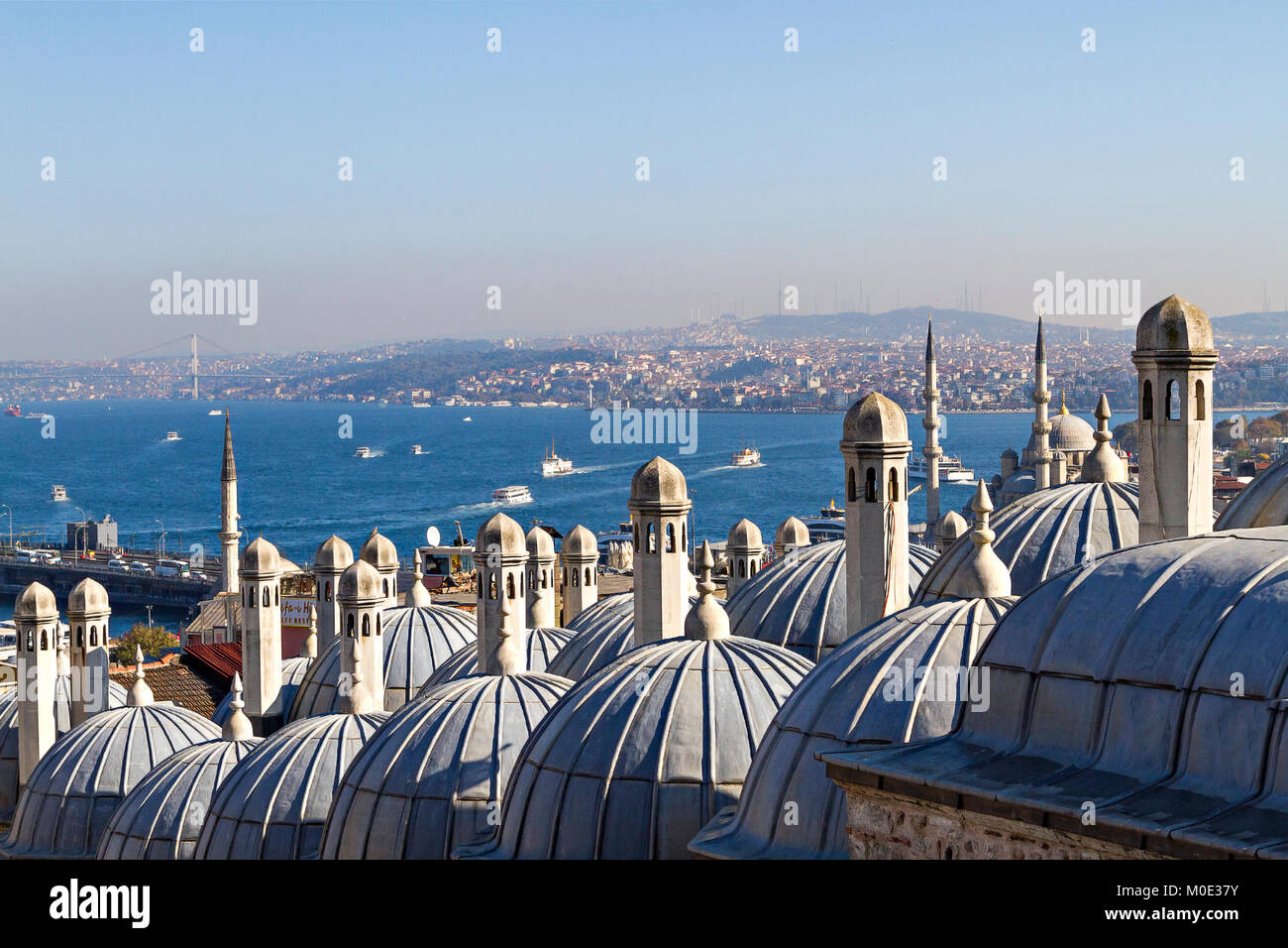 Bosforo attraverso i camini e le cupole dell'antica madrasa ottomana a Suleymaniye, Istanbul, Turchia. Foto Stock