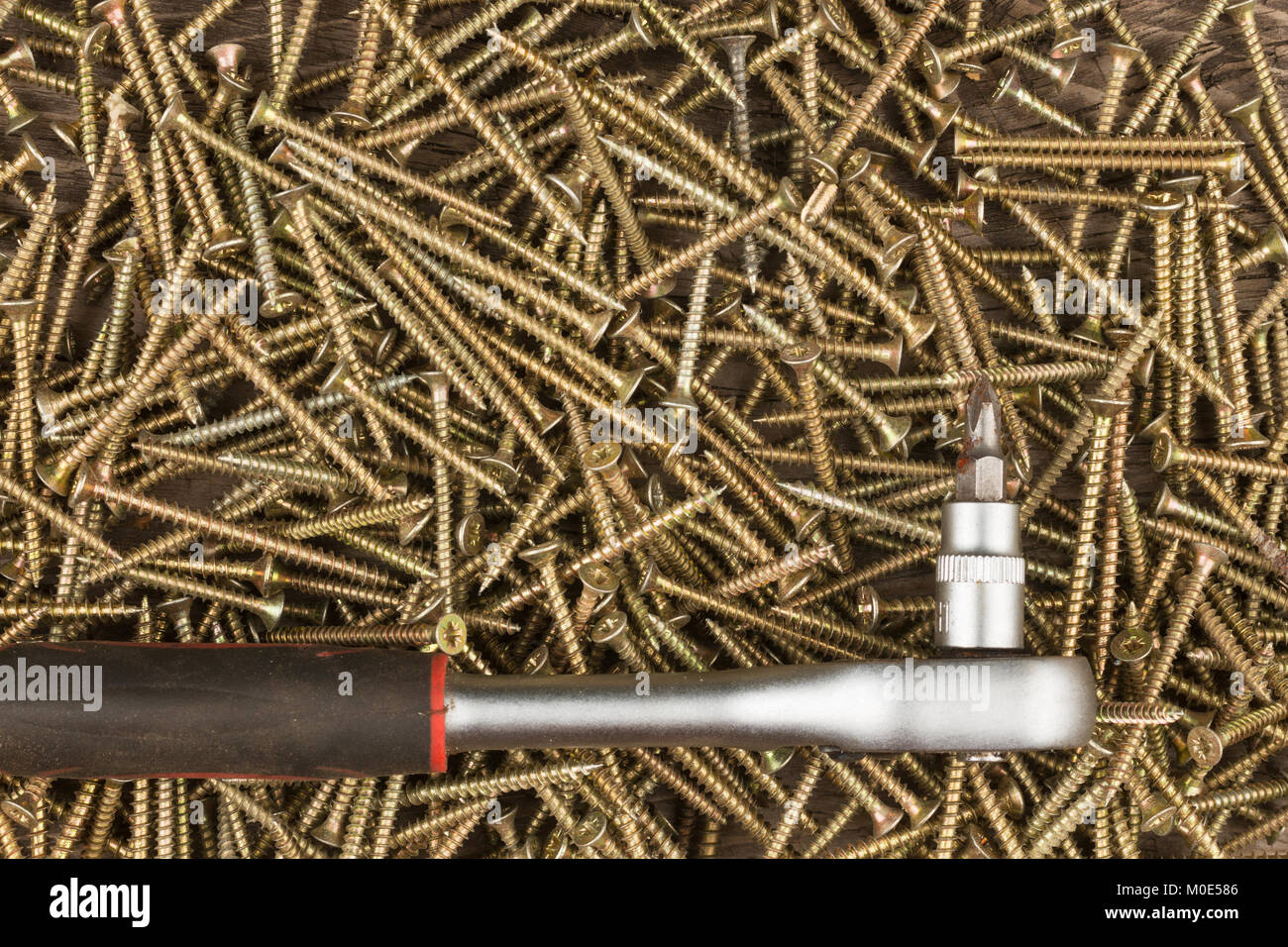 Chiave con testa di avvitamento giace contro lo sfondo delle viti. Close-up, la costruzione e la riparazione Foto Stock