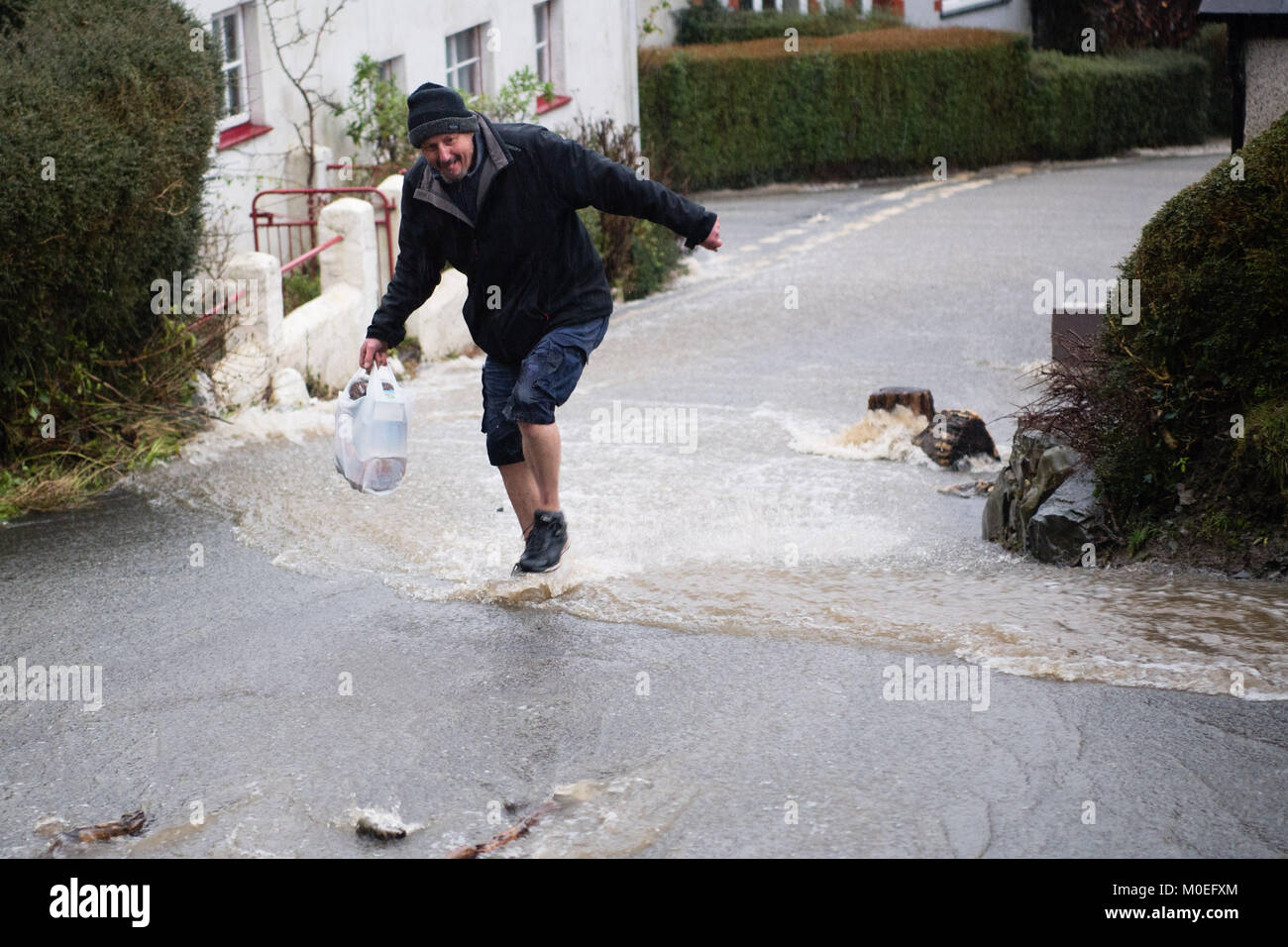 Llandre, Ceredigion nel Galles, domenica 21 gennaio 2018 UK Meteo: acqua di inondazione a cascata di un fiume lungo la strada principale di LLANDRE vicino a Aberystwyth in Galles Centrale, dopo ore di piogge torrenziali hanno causato il piccolo vapore che corre attraverso il villaggio di burst drasticamente le sue banche . I residenti locali realizzati improvvisate con sacchi di sabbia e barriere per cercare di deviare l'acqua lontano dalle loro case. Il flusso chiamate di overflow in alto sopra il villaggio appena al di fuori della chiesa parrocchiale, inviando i detriti verso il basso e lavando via le parti di superficie stradale foto © Keith Morris / Alamy Live News Foto Stock