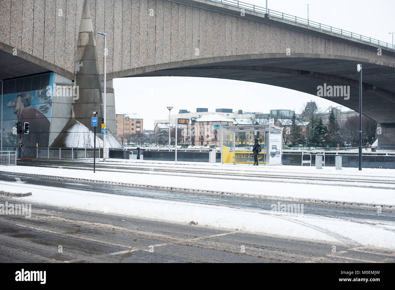 Glasgow, Regno Unito. Xxi gen, 2018. Un " commuter " attende ad una fermata autobus sotto il Kingston Bridge a Glasgow nella neve Credito: Tony Clerkson/Alamy Live News Foto Stock