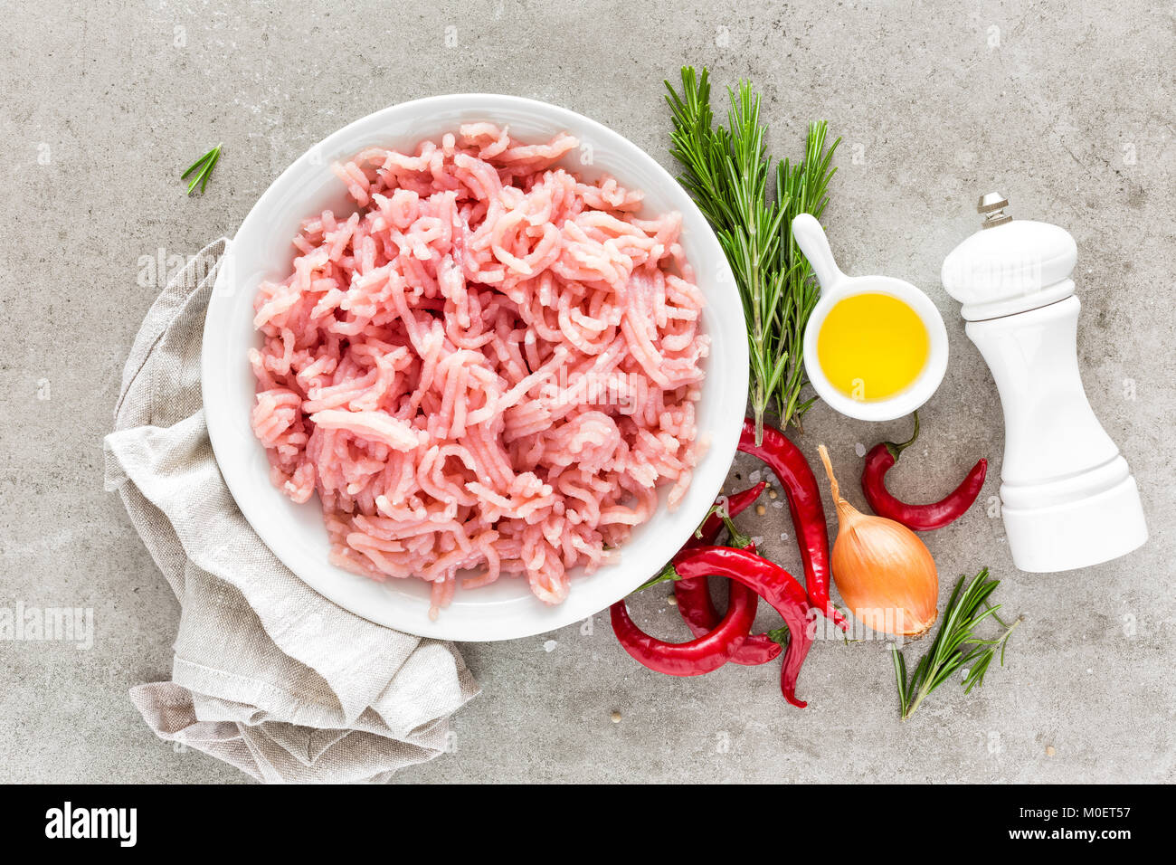 Tritare. La carne di suolo con gli ingredienti per la cottura su sfondo grigio chiaro. Vista superiore Foto Stock