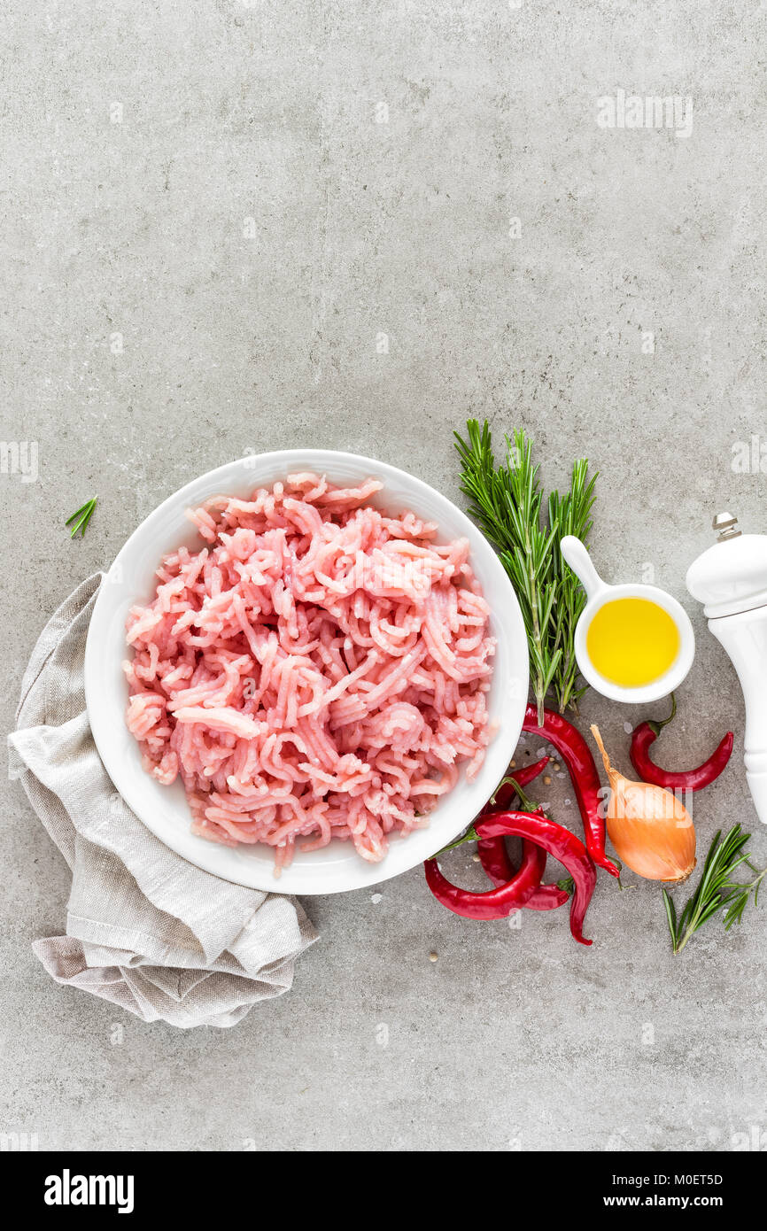 Tritare. La carne di suolo con gli ingredienti per la cottura su sfondo grigio chiaro. Vista superiore Foto Stock