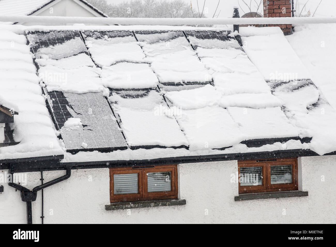 Pannelli solari sulla casa ricoperta di neve attorno alla diapositiva off, Llanfoist, Abergavenny, Wales, Regno Unito Foto Stock