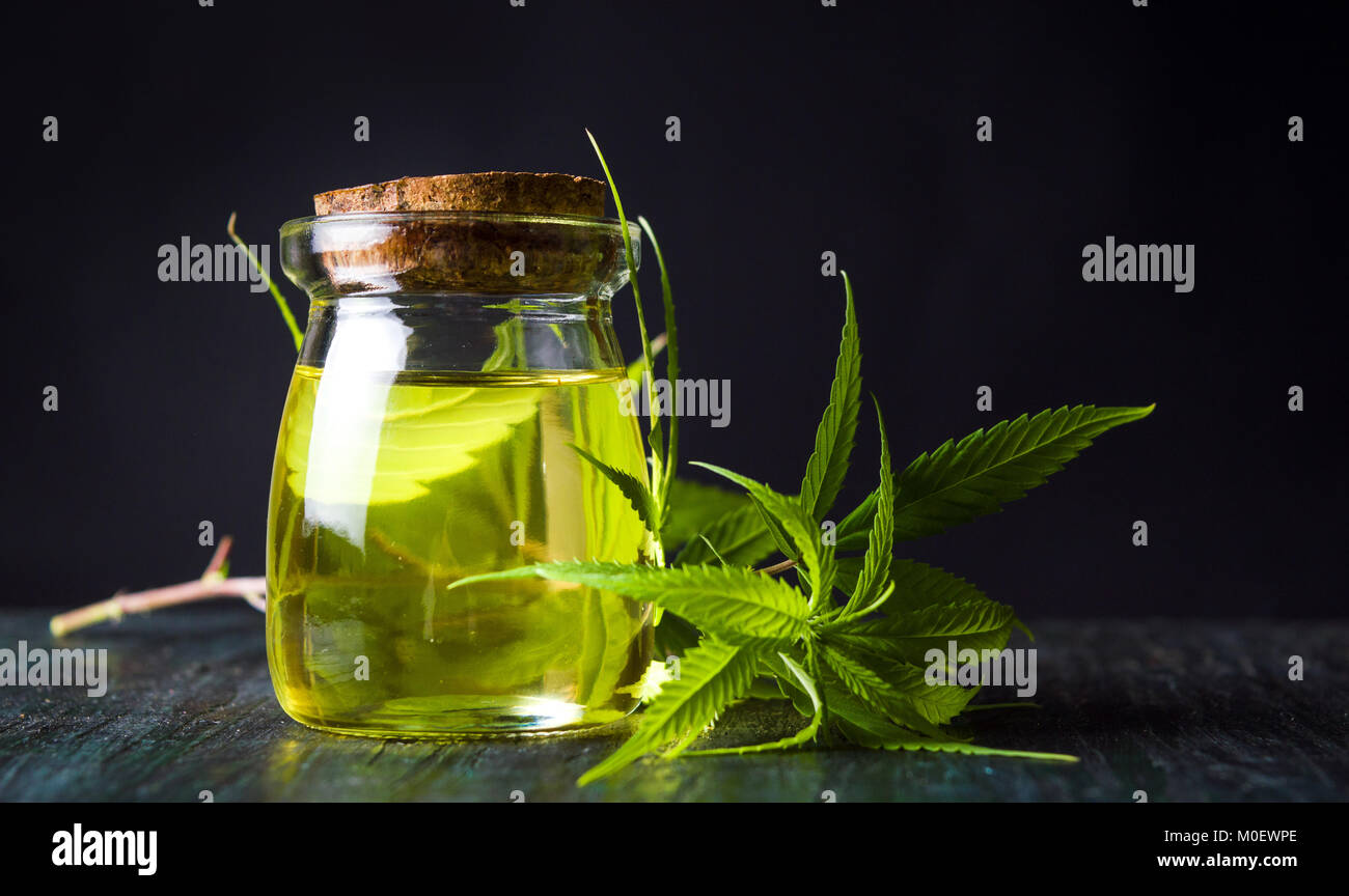 Olio di cannabis e foglie di marijuana sul tavolo di legno Foto Stock