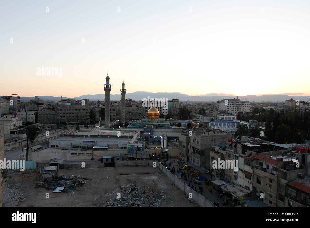 Colpo esterno per Sayeda Zeinab santuario in Damasco Capitale della Siria, che mostra il santuario con una cupola dorata e due minareti e alcuni residenti Foto Stock