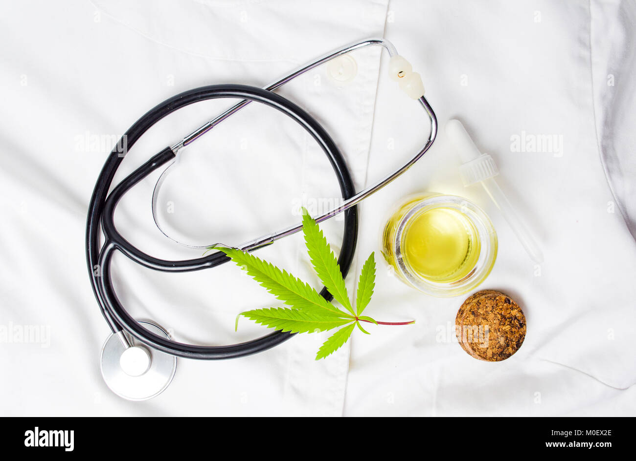 Foglia di marijuana, olio e uno stetoscopio sulla tuta medica Foto Stock