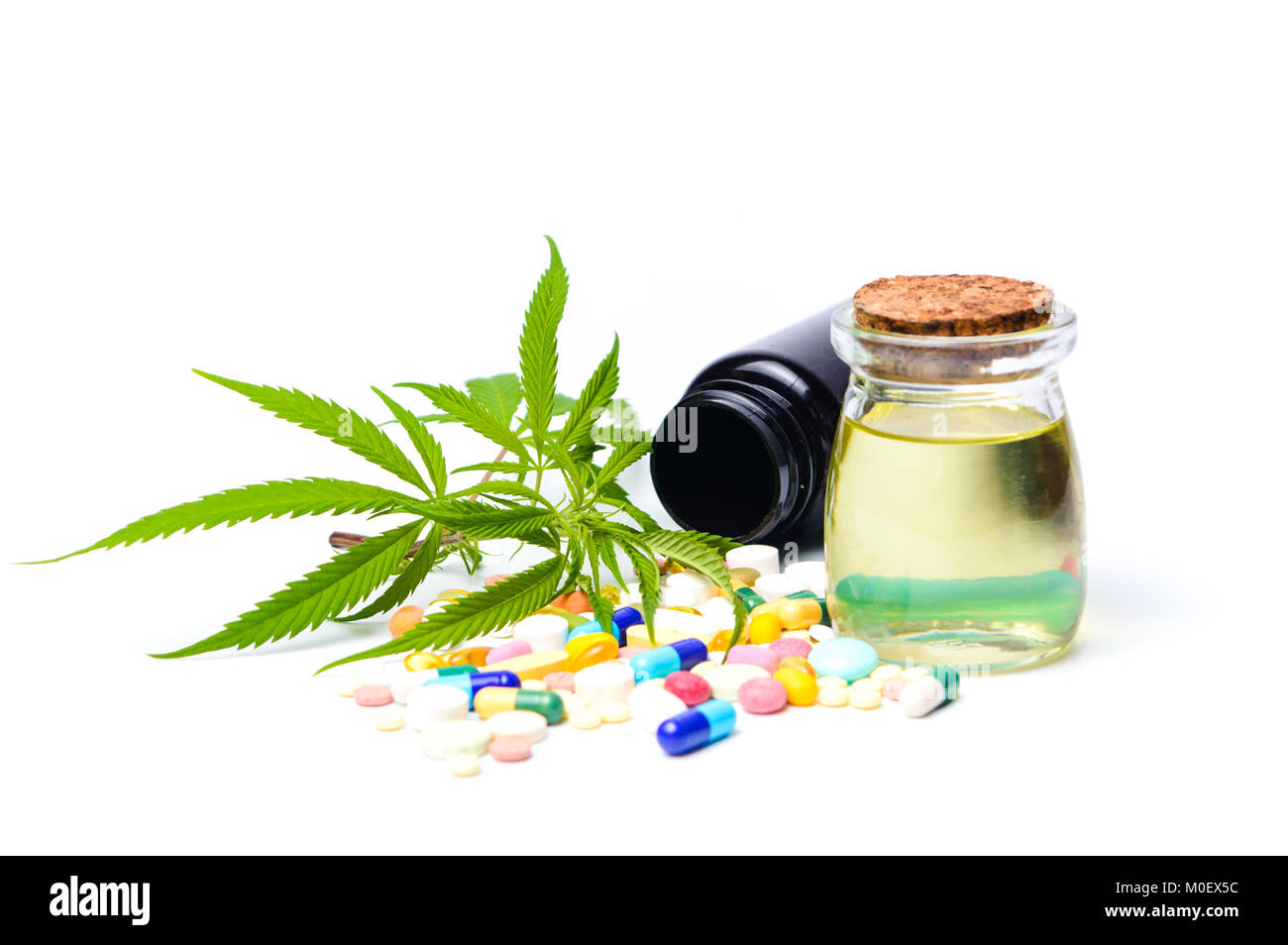 Olio di marijuana, foglie con medici pillole isolato su bianco Foto Stock