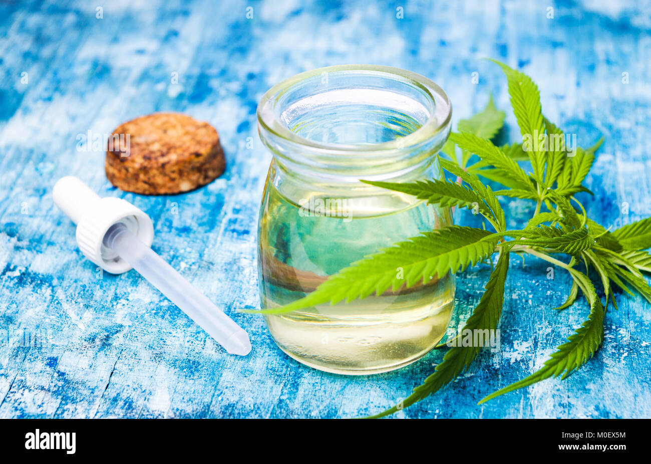 Olio di cannabis e foglie di marijuana sul tavolo di legno Foto Stock