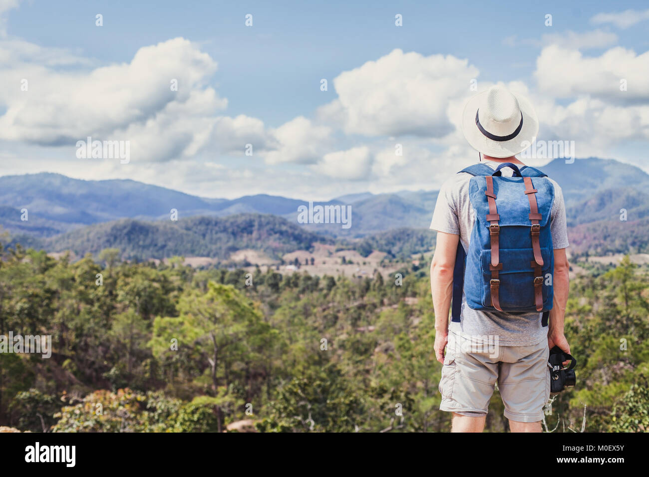 Estate trekking in montagna, turistico escursionista viaggi all'aperto, hipster con fotocamera zaino e guardando il paesaggio panoramico Foto Stock