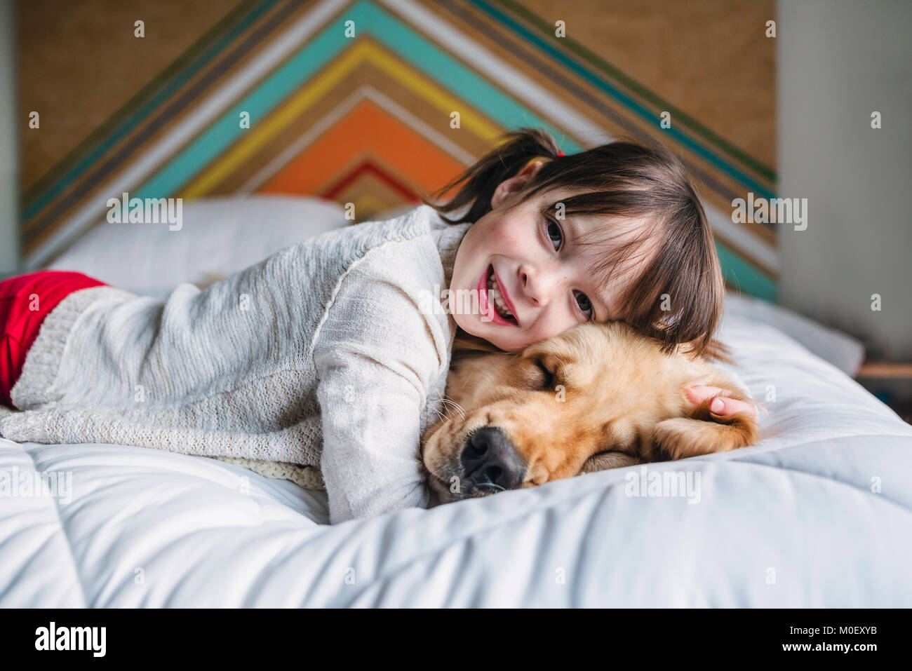 Ragazza distesa su un letto con il suo golden retriever cane Foto Stock