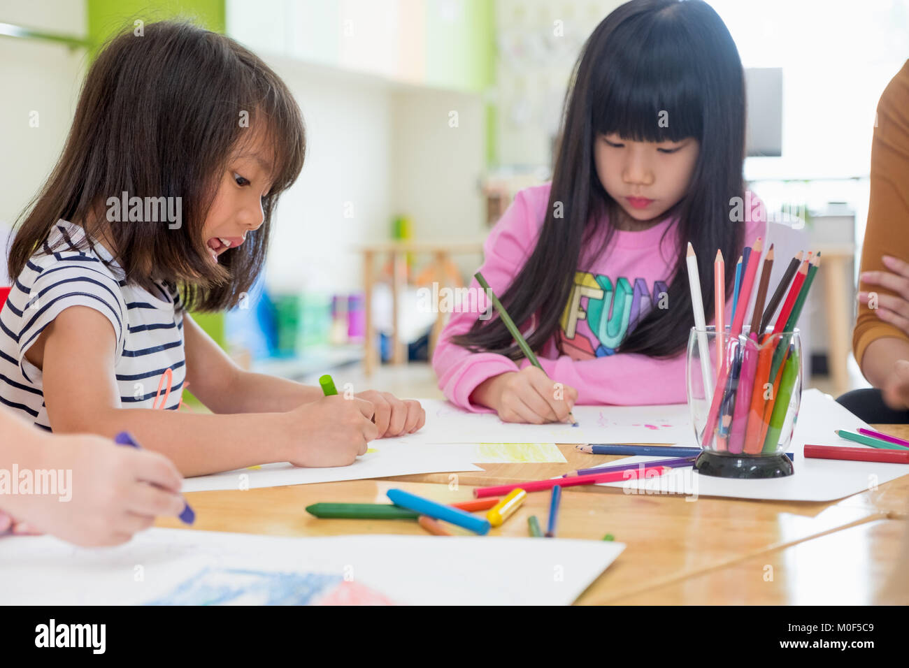 I bambini di età prescolare Disegno con matite colorate su carta bianca sulla tavola in aula con gli amici e il maestro,Kindergarten concetto di istruzione Foto Stock