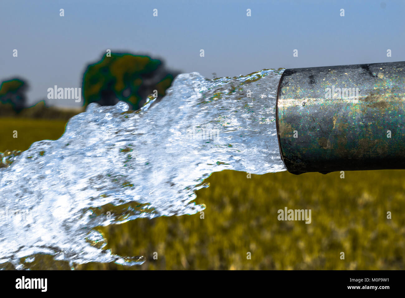 Crystal Clear e dolci acque salutari essendo a filo fuori da un pesante motore diesel tubo bene nei campi di grano dove il fiume di acqua non riesce a raggiungere il Foto Stock