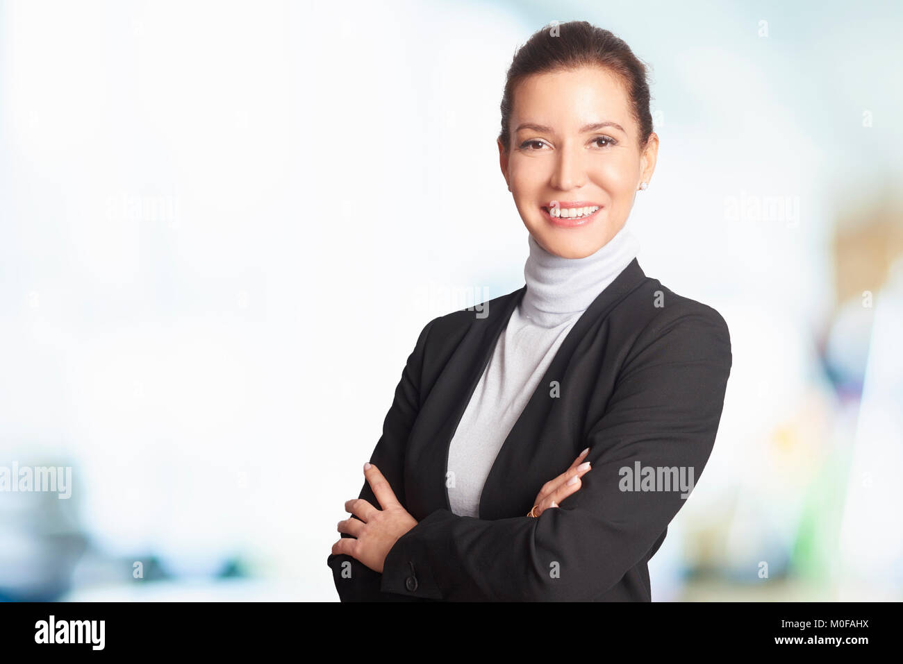 Un chief financial officer imprenditrice in piedi in ufficio mentre guardando la fotocamera e sorridente. Foto Stock