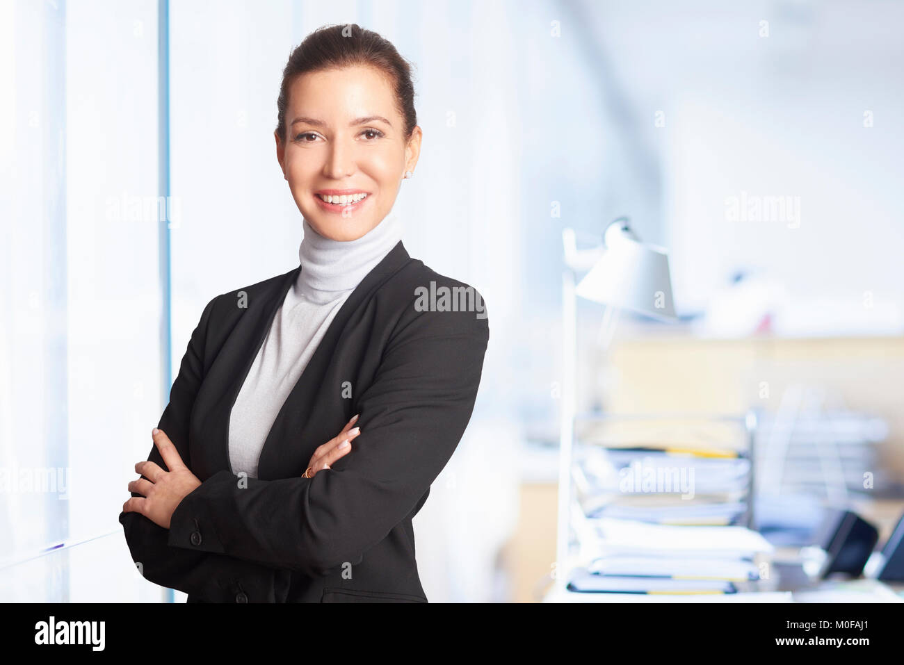 Un chief financial officer imprenditrice in piedi in ufficio mentre guardando la fotocamera e sorridente. Foto Stock