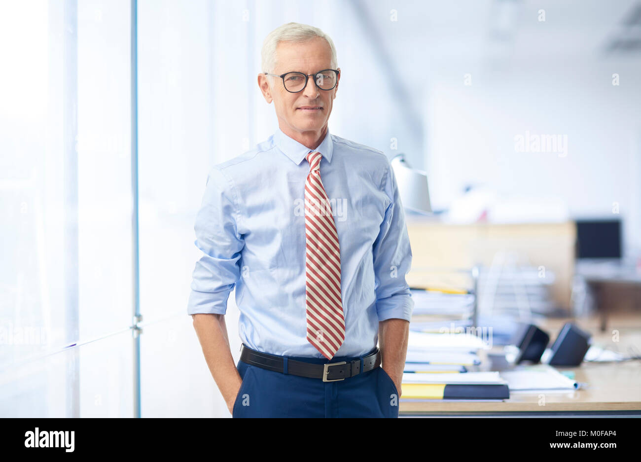 Imprenditore Senior indossando arrotolato a maniche camicia e cravatta mentre in piedi presso l'ufficio. Foto Stock