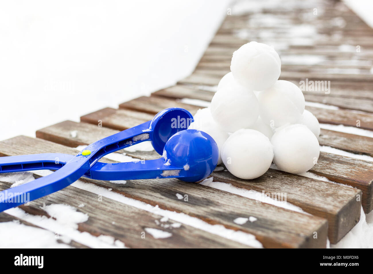 Plastica blu snowball maker con set di pronto snowballs posa su un banco di legno vicino all'aperto il parco giochi per i bambini al giorno d'inverno. Foto Stock