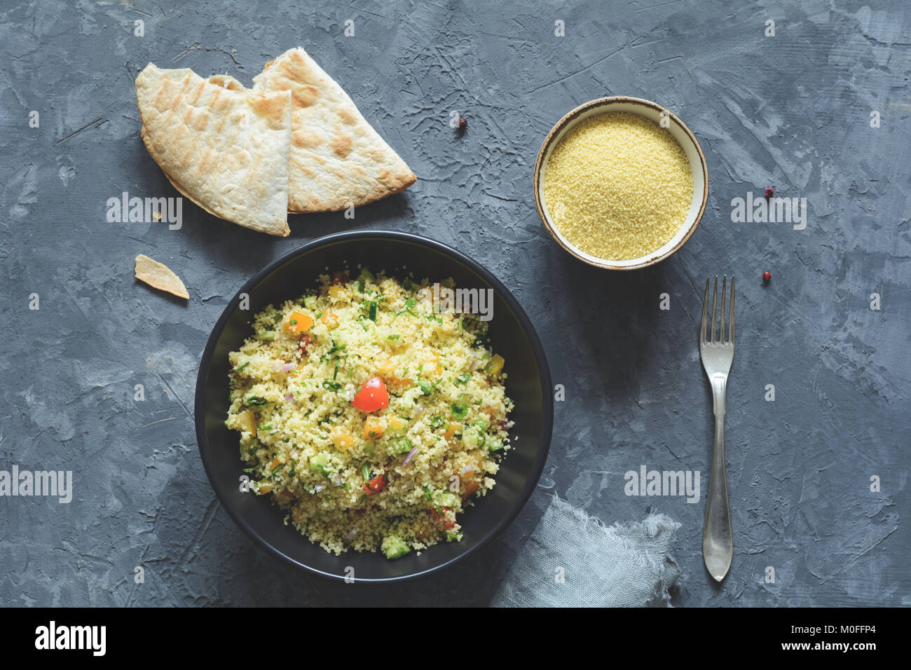 Tabulé con cous cous e arabo flatbread su sfondo di calcestruzzo. Un sano pasto dietetico. Tabella vista superiore Foto Stock