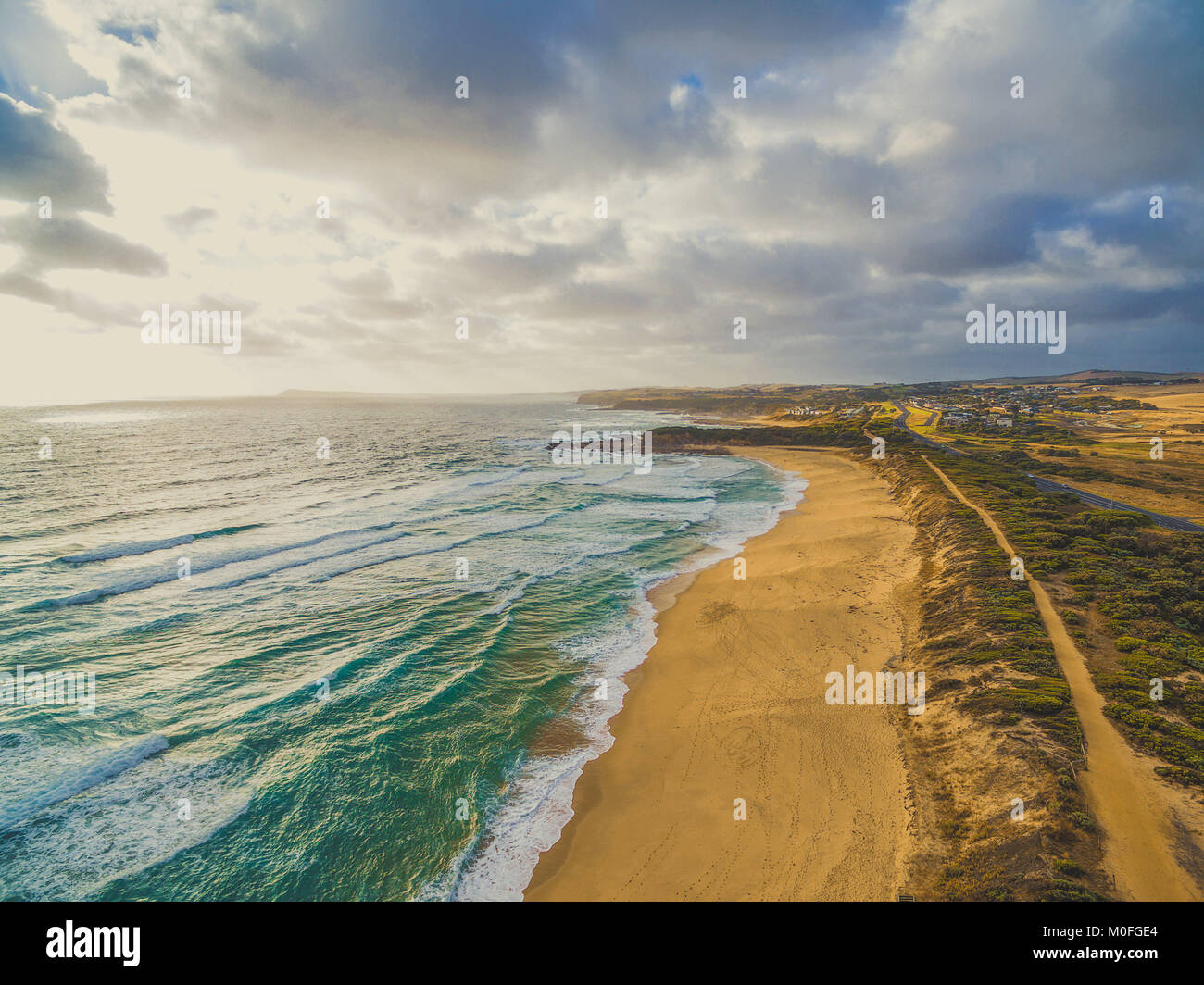 Suggestivo panorama della fascia costiera sull'oceano giallo con spiaggia di sabbia e nelle aree rurali. Kilcunda, Victoria, Australia Foto Stock