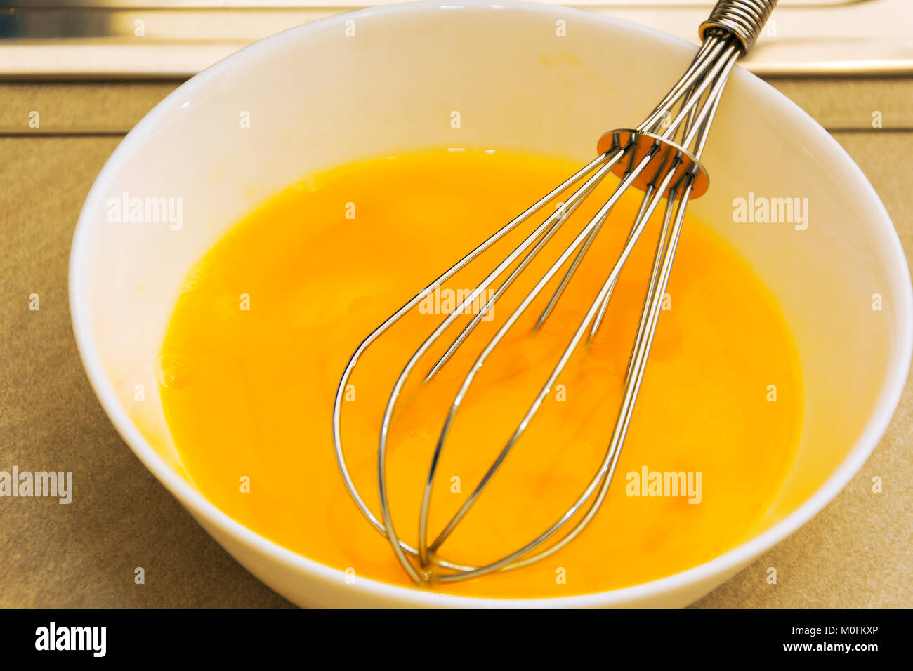 Cucina metallica mescolare con una frusta in un giallo di pasta all'uovo Foto Stock
