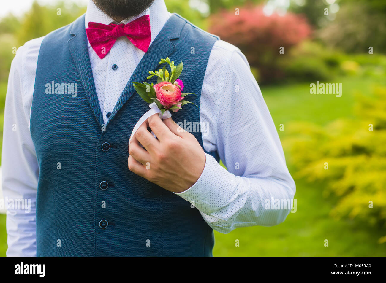 Frammento di lusso abito sposo in camicia bianca e blu giubbotto di cotone e i dettagli di rosa sul verde sfondo all'aperto Foto Stock