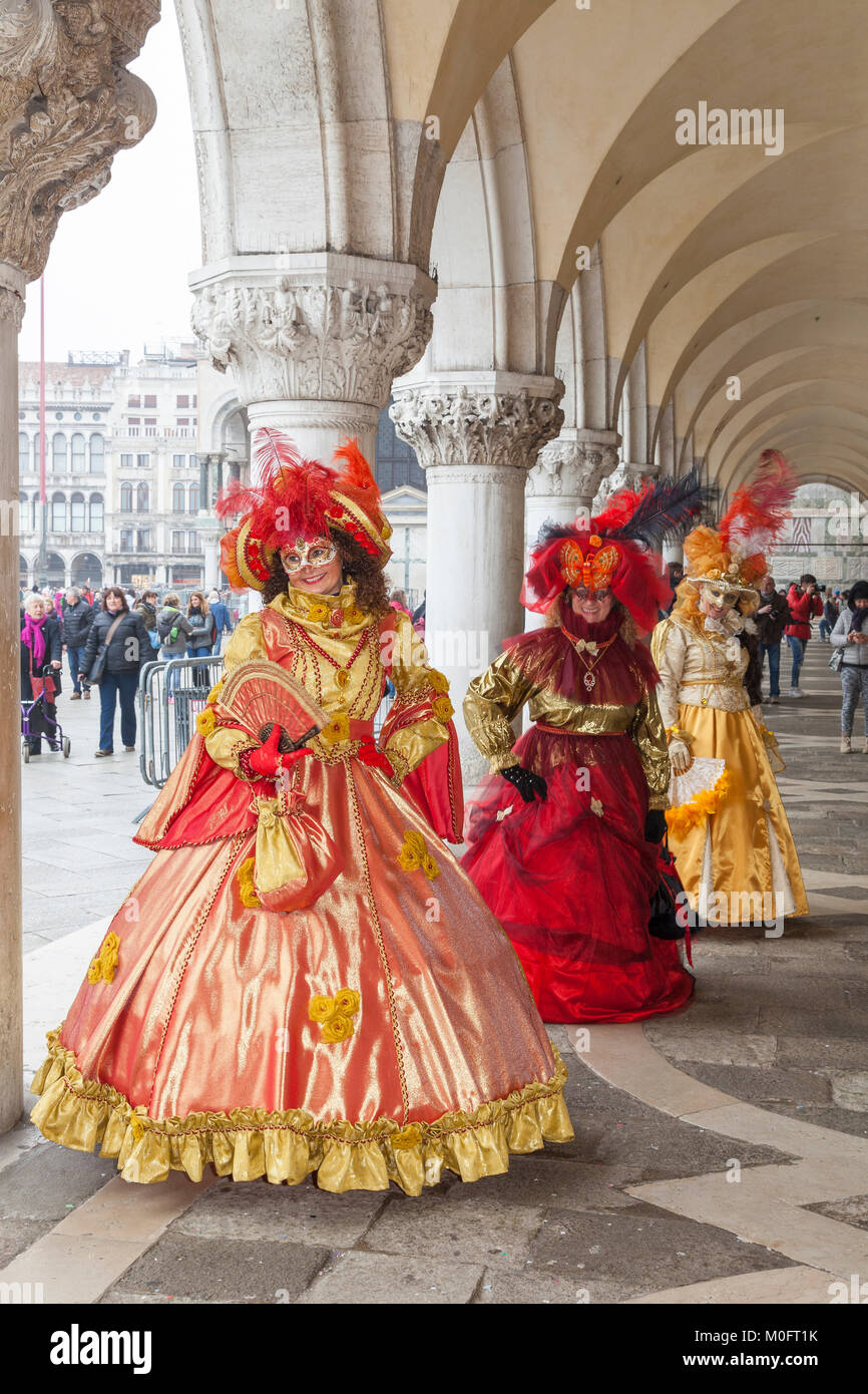 Il Carnevale di Venezia, Venezia, Italia. Tre donne in costumi classic in posa presso il Palazzo dei Dogi, San Marco, sotto gli archi Foto Stock